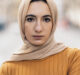 Expressive young muslim woman standing in the street wearing hijab and looking at camera.